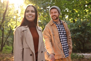 Photo of Beautiful couple walking together in autumn park, selective focus