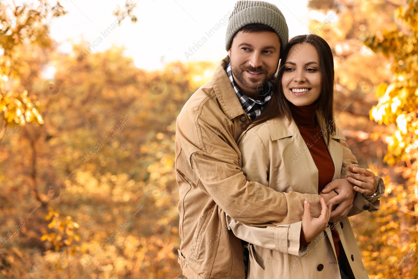 Photo of Beautiful couple hugging outdoors on autumn day, space for text