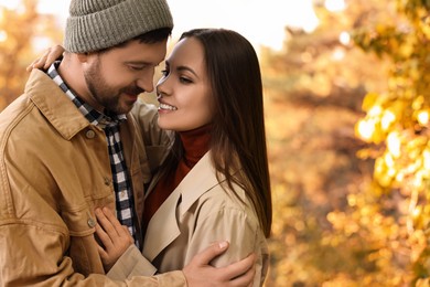 Photo of Beautiful couple hugging outdoors on autumn day, space for text