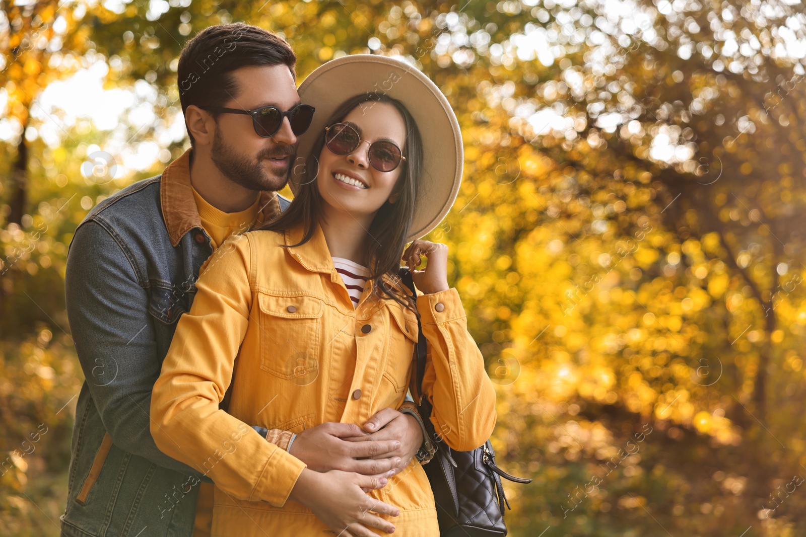 Photo of Beautiful couple hugging in park on autumn day, space for text