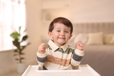 Cute little kid sitting in high chair at home