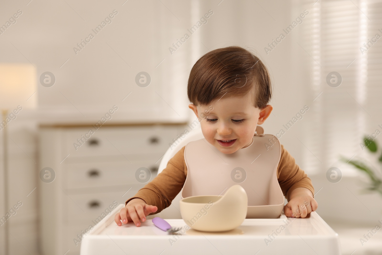 Photo of Cute little baby eating healthy food from bowl in high chair at home, space for text