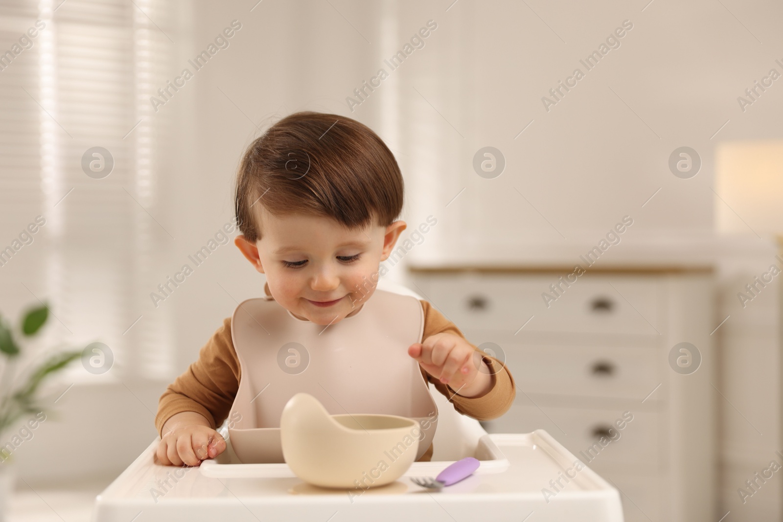 Photo of Cute little baby eating healthy food from bowl in high chair at home, space for text