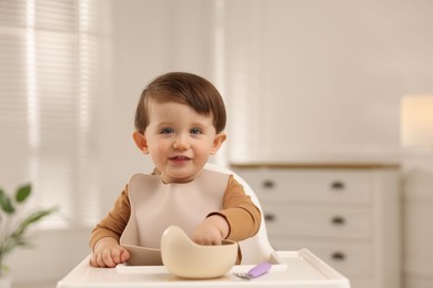 Photo of Cute little baby eating healthy food from bowl in high chair at home, space for text