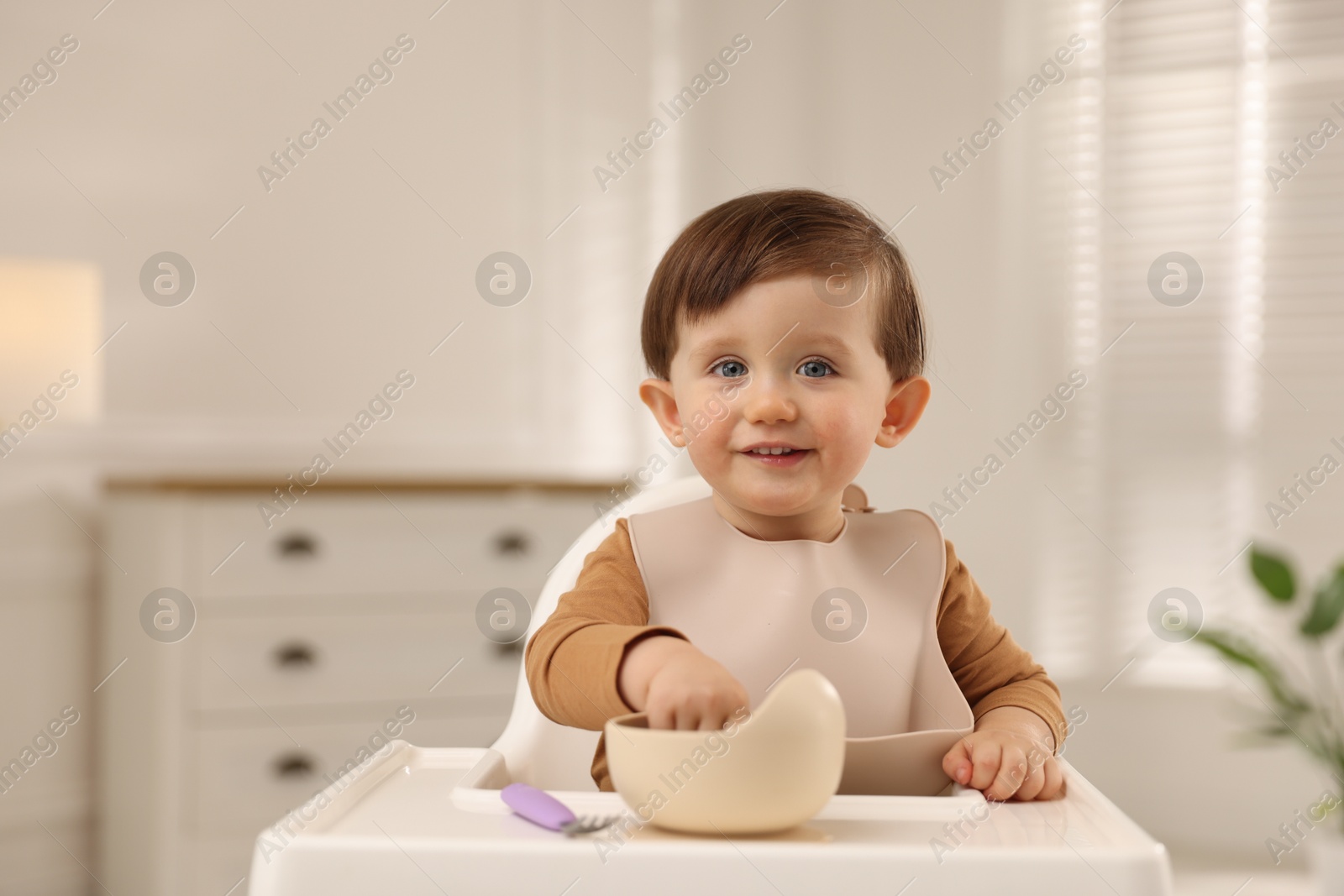 Photo of Cute little baby eating healthy food from bowl in high chair at home, space for text