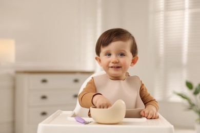 Photo of Cute little baby eating healthy food from bowl in high chair at home, space for text