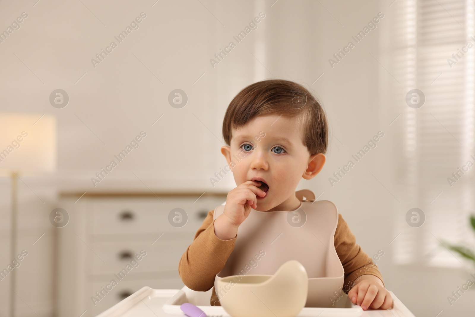 Photo of Cute little baby eating healthy food from bowl in high chair at home, space for text