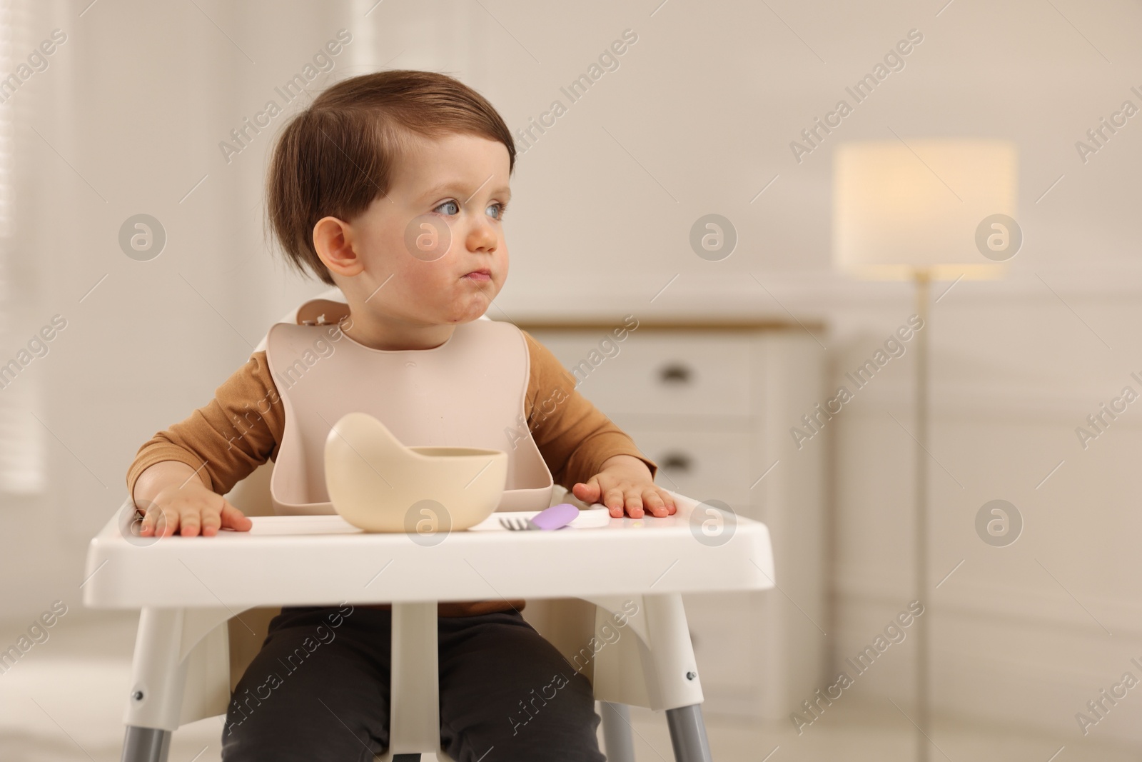 Photo of Cute little baby eating healthy food from bowl in high chair at home, space for text