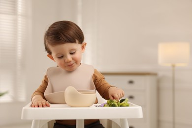 Photo of Cute little baby eating healthy food from bowl in high chair at home, space for text