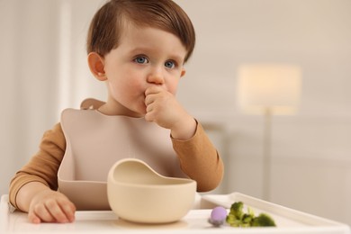 Photo of Cute little baby eating healthy food from bowl in high chair at home, space for text