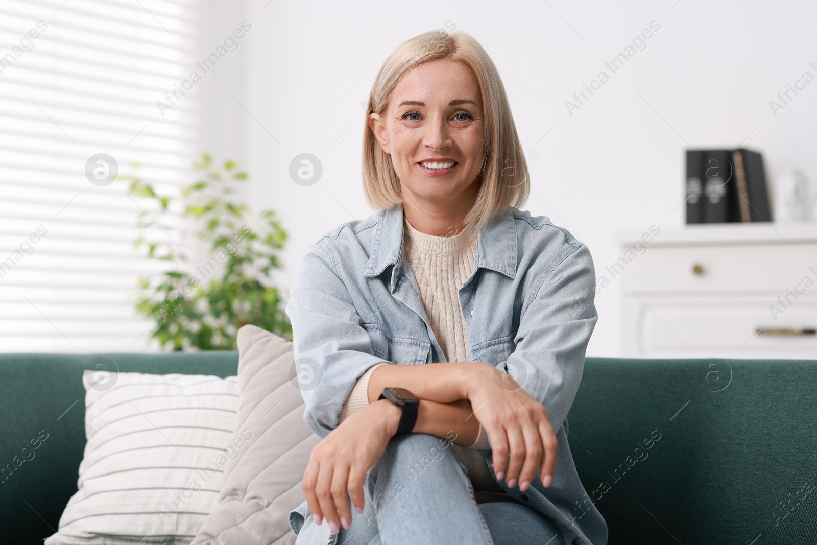 Photo of Portrait of smiling middle aged woman on sofa at home