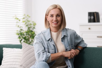 Portrait of smiling middle aged woman on sofa at home