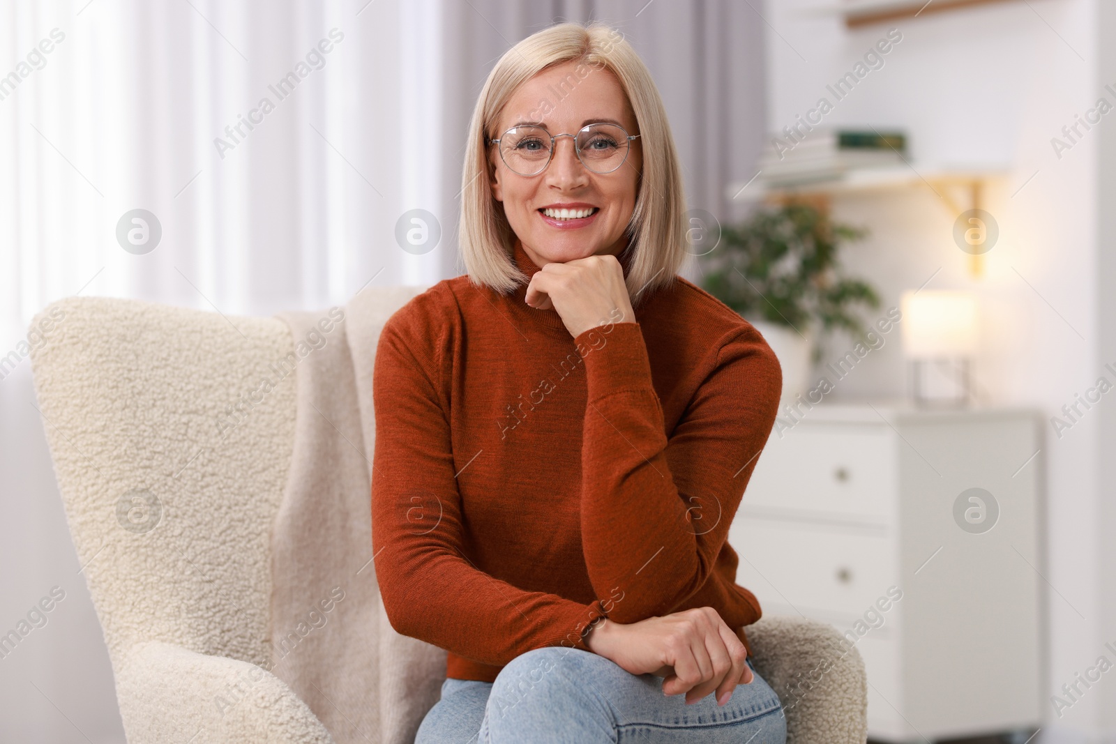 Photo of Portrait of smiling middle aged woman on armchair at home