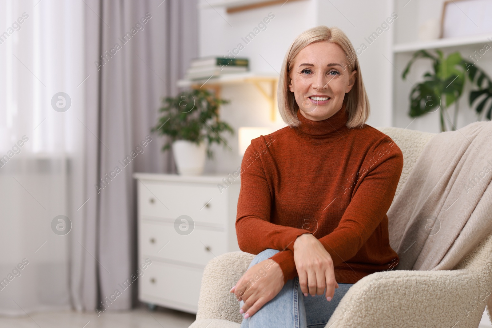 Photo of Portrait of smiling middle aged woman on armchair at home. Space for text