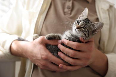 Photo of Man with cute kitten at home, closeup