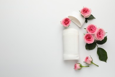 Photo of Solid deodorant and beautiful rose flowers on white background, flat lay. Space for text