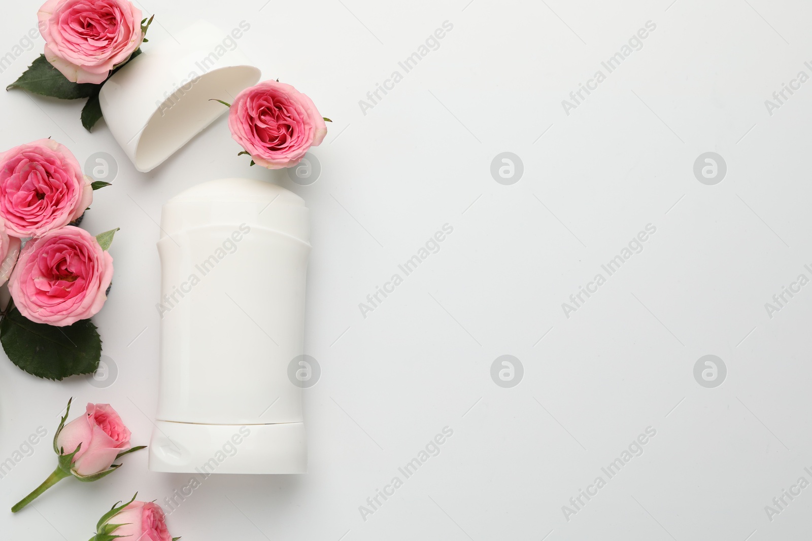 Photo of Solid deodorant and beautiful rose flowers on white background, flat lay. Space for text