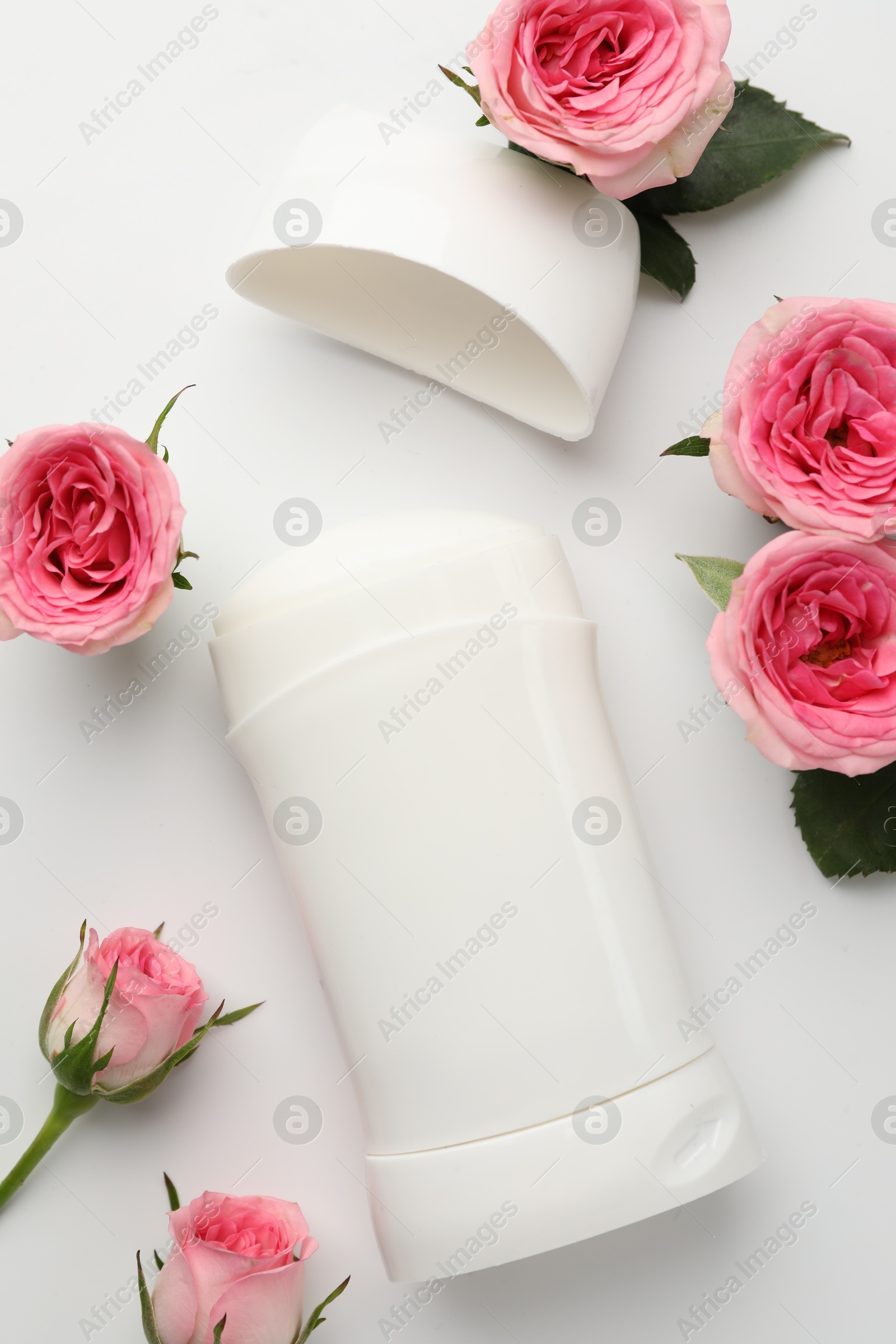 Photo of Solid deodorant and beautiful rose flowers on white background, flat lay