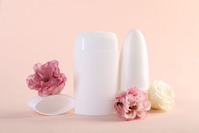 Photo of Different deodorants and beautiful eustoma flowers on beige background