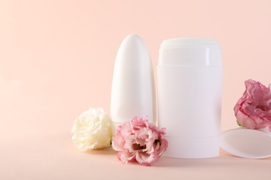 Photo of Different deodorants and beautiful eustoma flowers on beige background