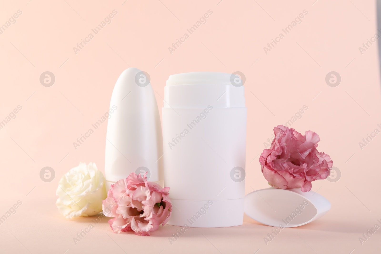 Photo of Different deodorants and beautiful eustoma flowers on beige background