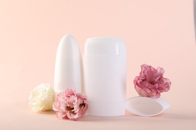 Photo of Different deodorants and beautiful eustoma flowers on beige background