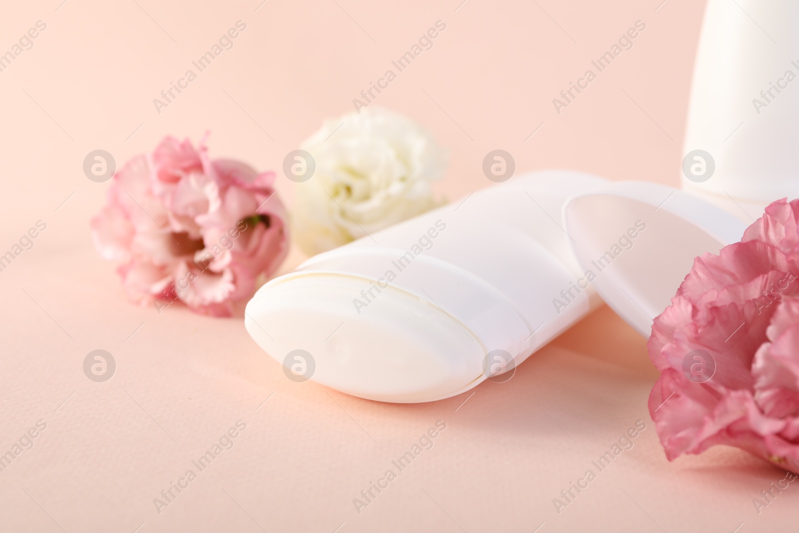 Photo of Solid deodorant and beautiful eustoma flowers on beige background, closeup