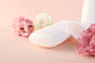 Photo of Solid deodorant and beautiful eustoma flowers on beige background, closeup