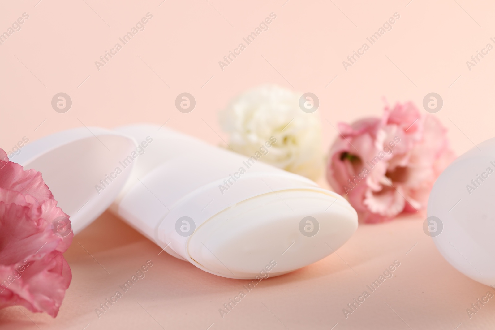 Photo of Solid deodorant and beautiful eustoma flowers on beige background, closeup