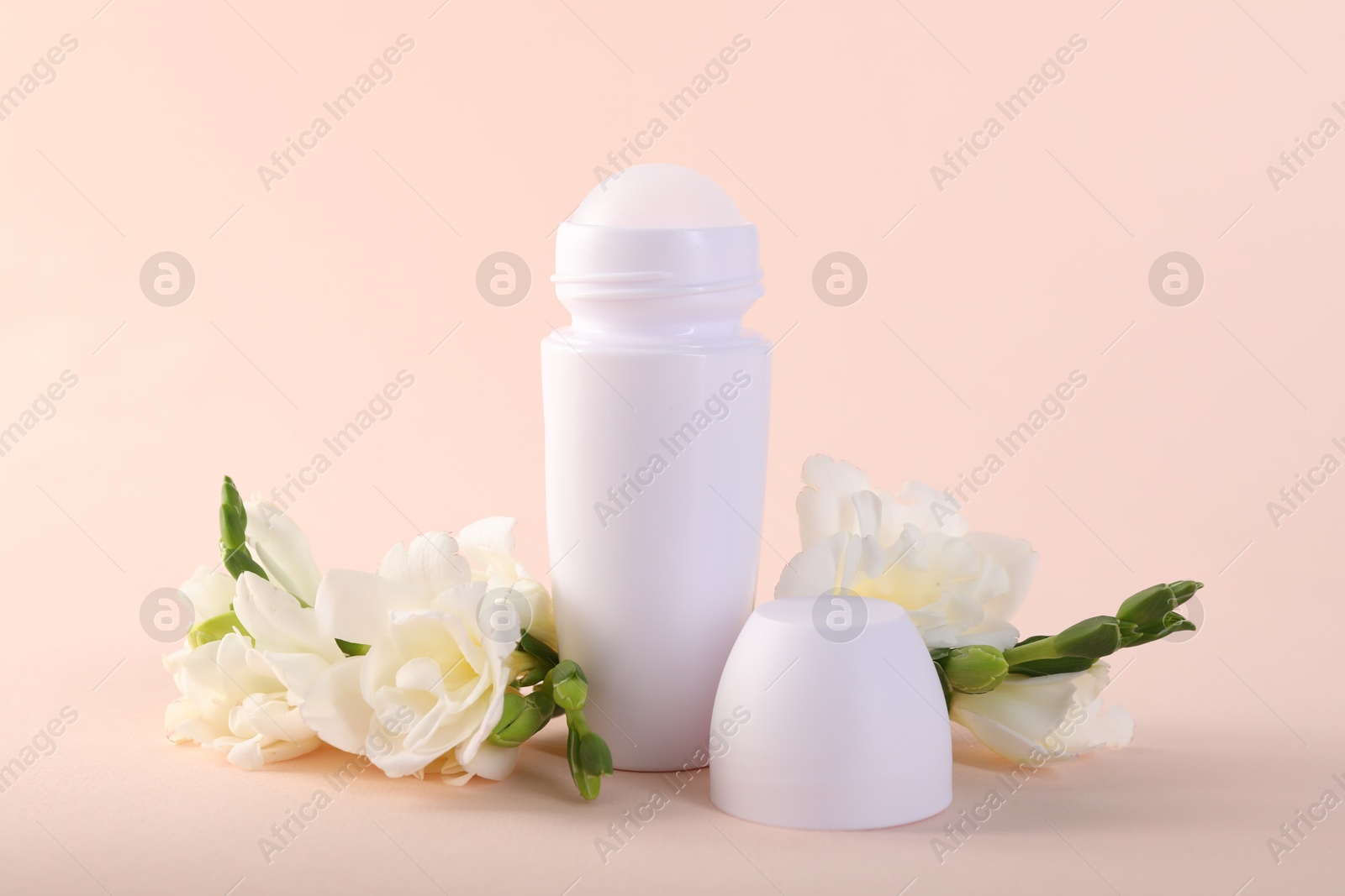 Photo of Roll-on deodorant and beautiful eustoma flowers on beige background