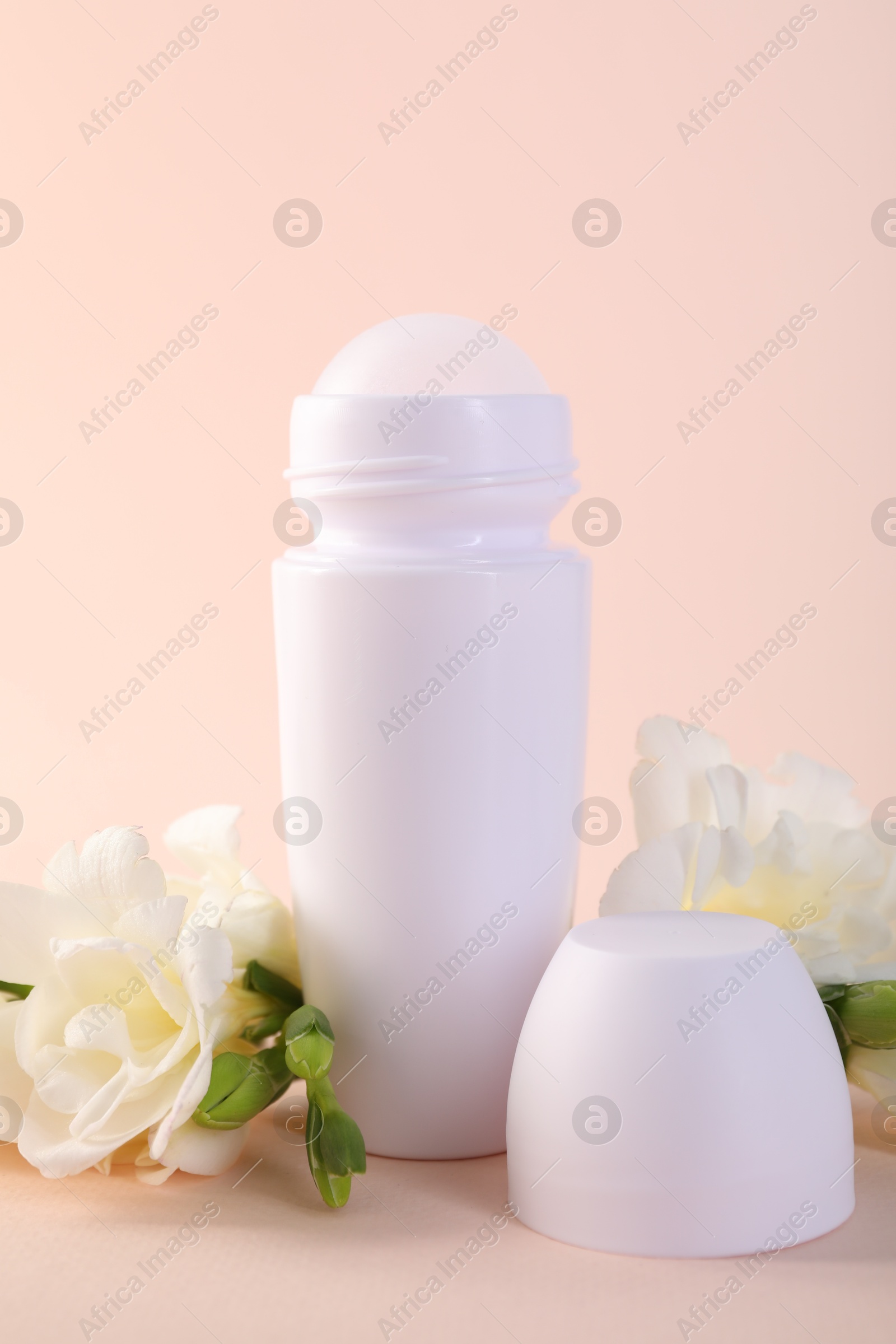 Photo of Roll-on deodorant and beautiful eustoma flowers on beige background