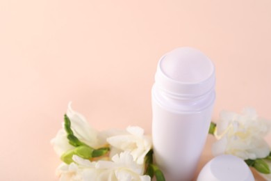 Photo of Roll-on deodorant and beautiful eustoma flowers on beige background, closeup