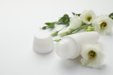 Photo of Roll-on deodorant and beautiful eustoma flowers on white background, closeup