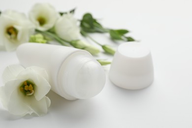 Photo of Roll-on deodorant and beautiful eustoma flowers on white background, closeup