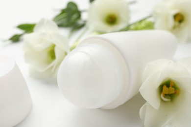 Roll-on deodorant and beautiful eustoma flowers on white background, closeup