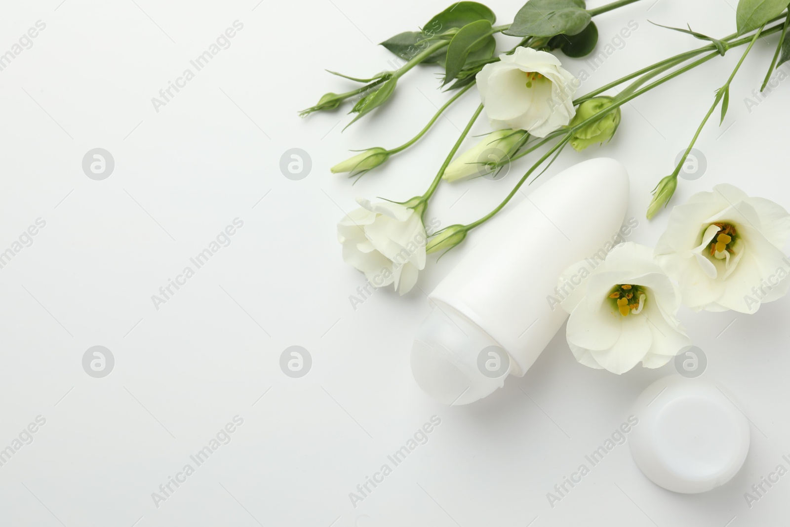 Photo of Roll-on deodorant and beautiful eustoma flowers on white background, flat lay. Space for text