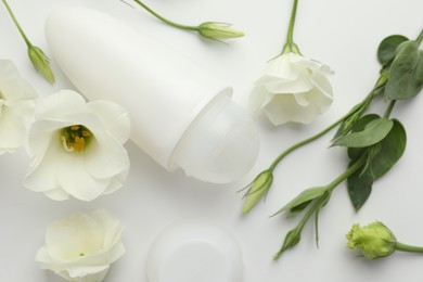 Photo of Roll-on deodorant and beautiful eustoma flowers on white background, flat lay