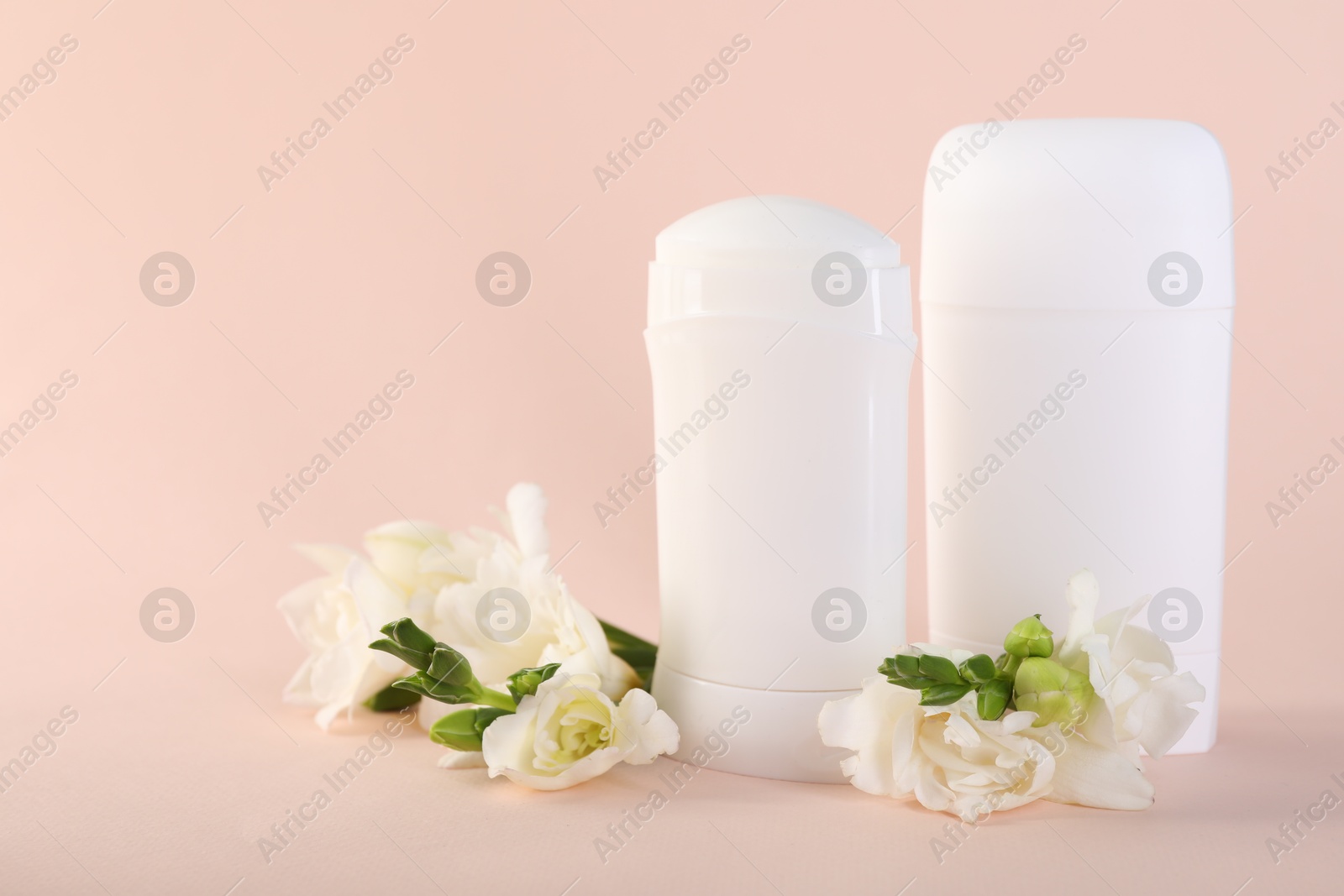 Photo of Solid deodorants and beautiful eustoma flowers on beige background