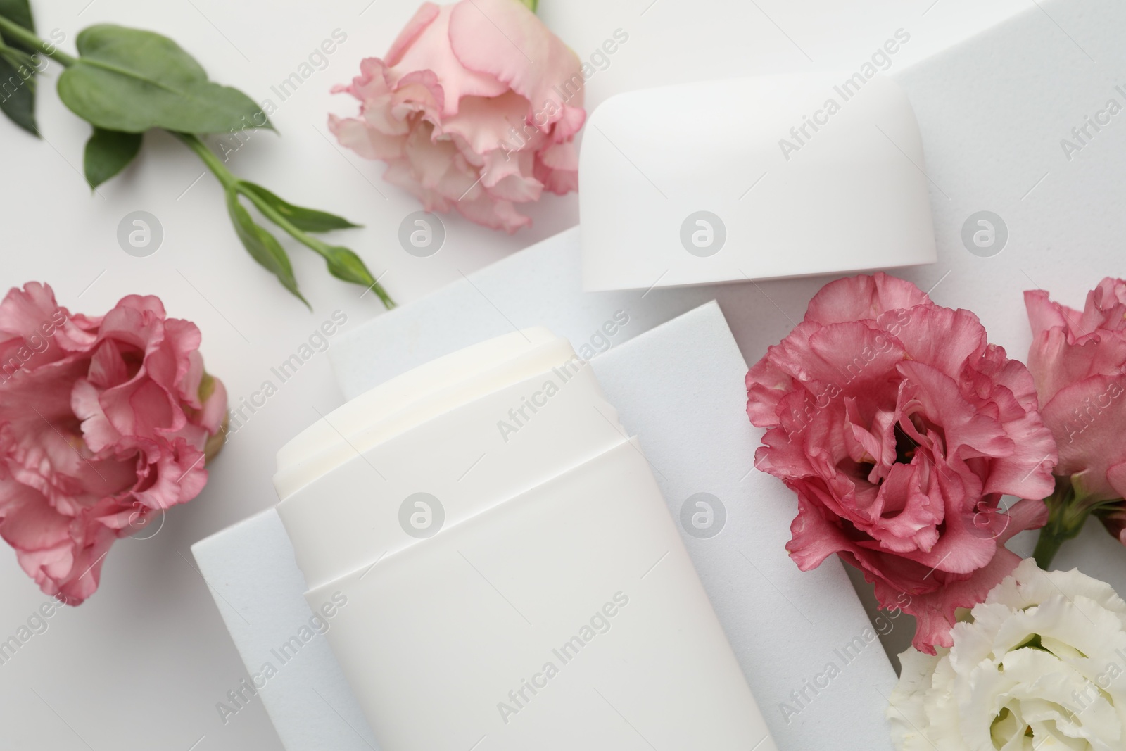 Photo of Solid deodorant and beautiful eustoma flowers on white background, top view