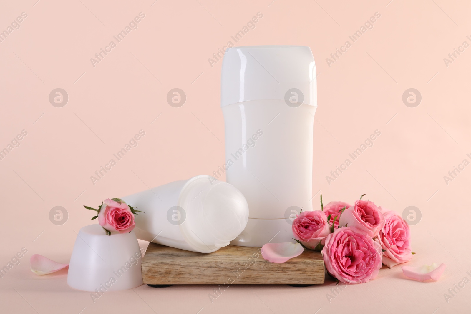 Photo of Different deodorants and beautiful rose flowers on beige background