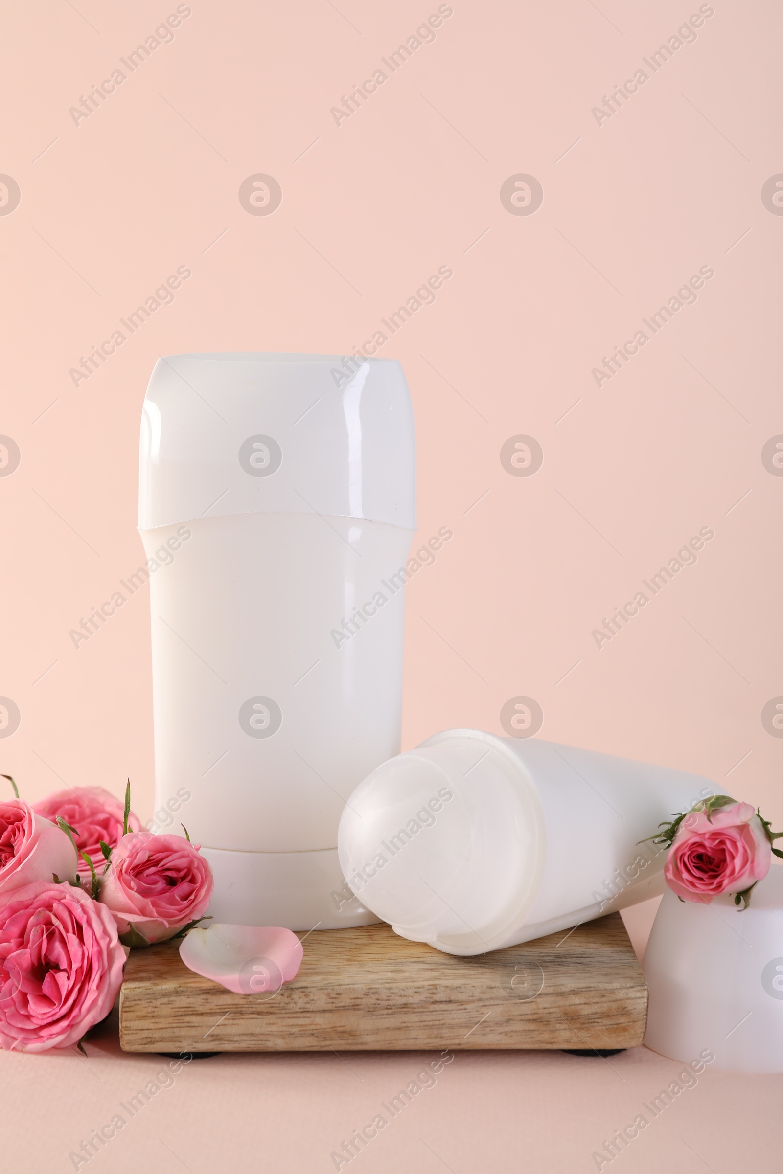 Photo of Different deodorants and beautiful rose flowers on beige background