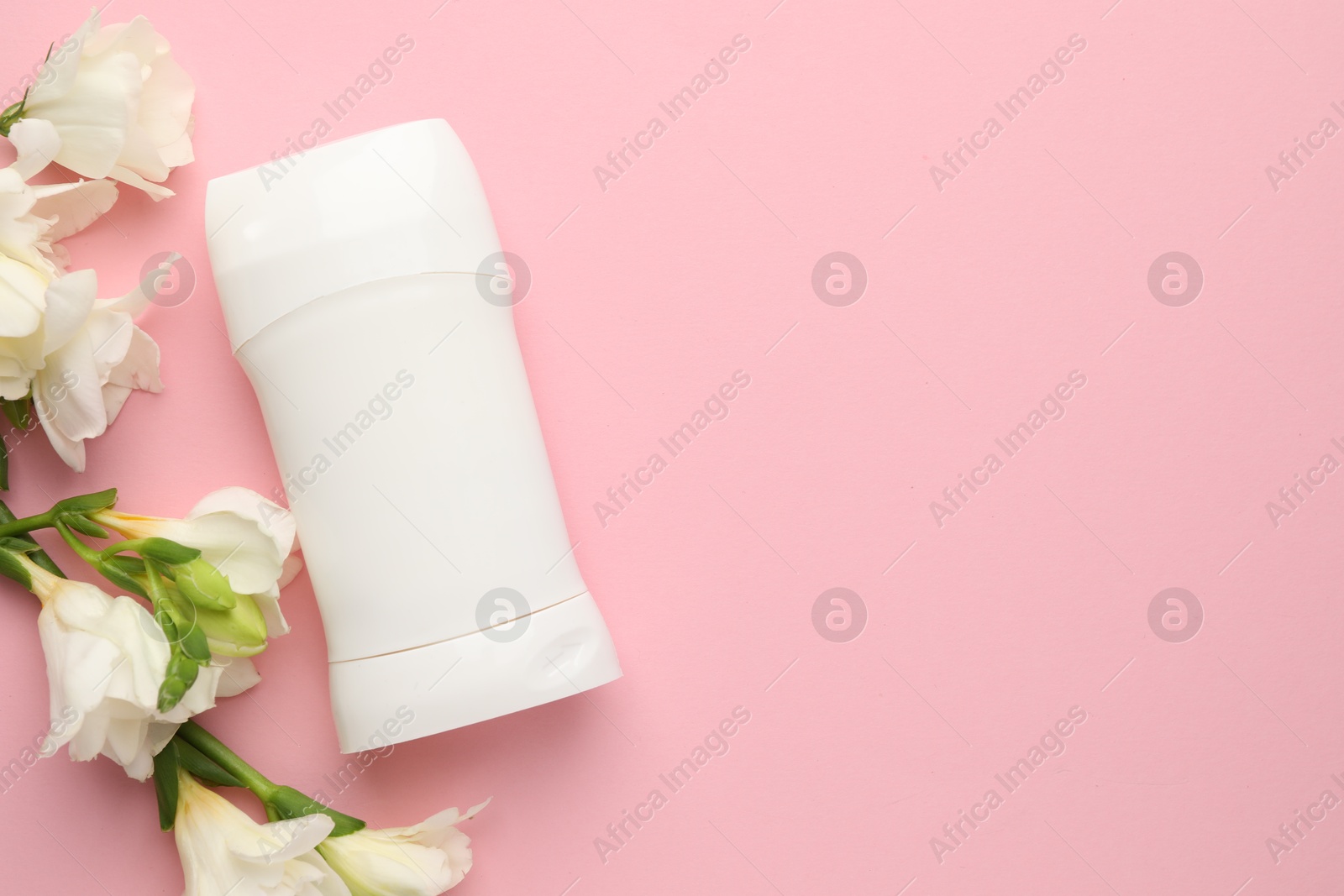 Photo of Solid deodorant and beautiful eustoma flowers on pink background, flat lay. Space for text