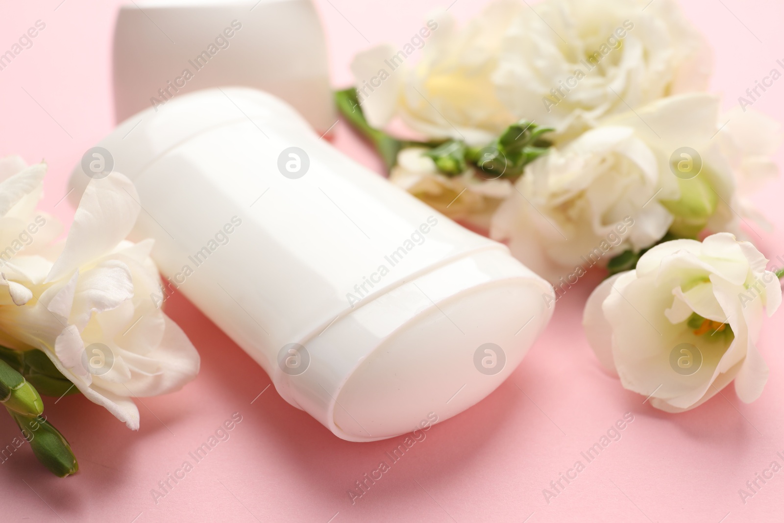 Photo of Solid deodorant and beautiful eustoma flowers on pink background, closeup