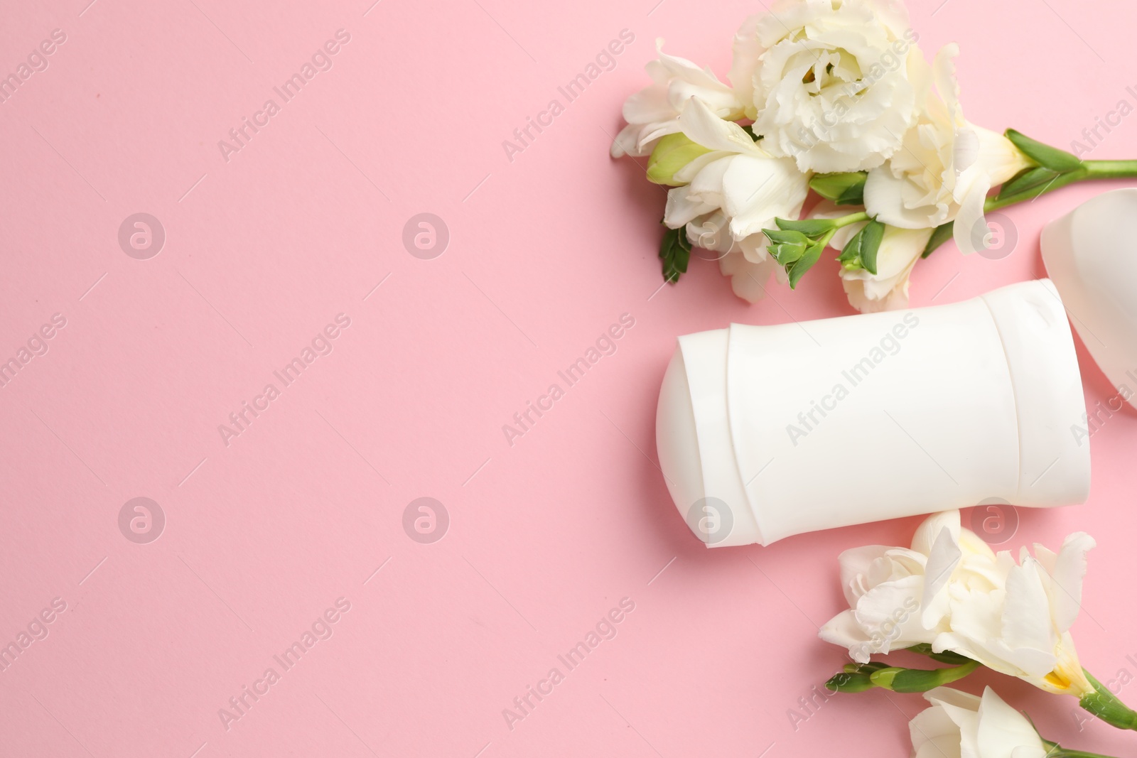 Photo of Solid deodorant and beautiful eustoma flowers on pink background, flat lay. Space for text