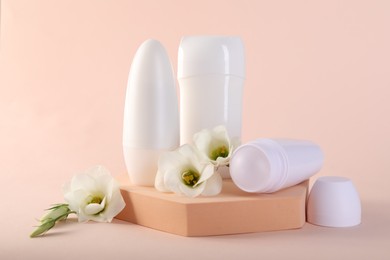 Photo of Different deodorants and beautiful eustoma flowers on beige background