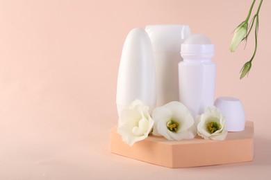 Photo of Different deodorants and beautiful eustoma flowers on beige background, space for text