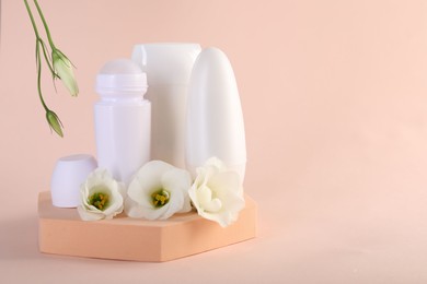 Photo of Different deodorants and beautiful eustoma flowers on beige background, space for text