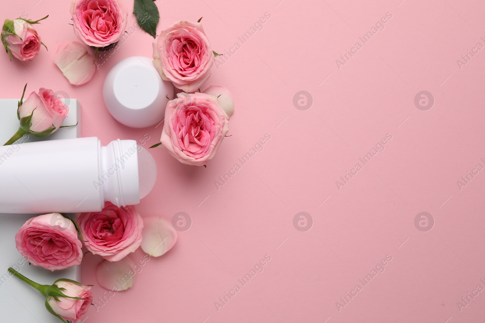 Photo of Roll-on deodorant and beautiful rose flowers on pink background, flat lay. Space for text