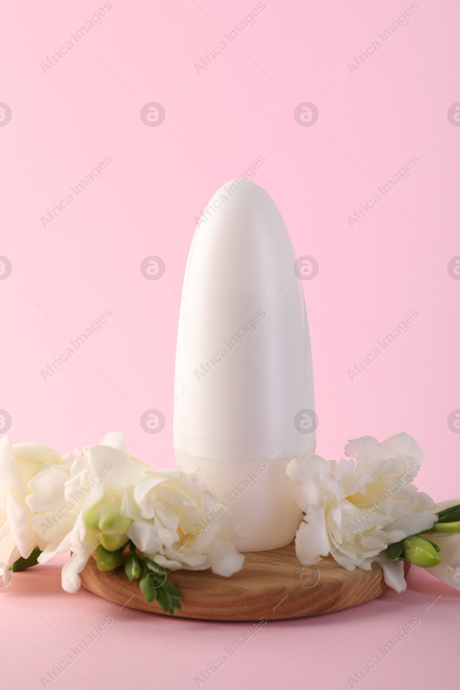 Photo of Roll-on deodorant and beautiful eustoma flowers on pink background