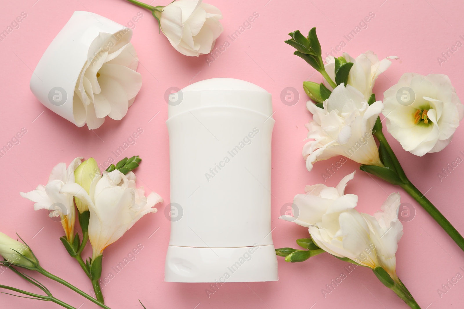 Photo of Solid deodorant and beautiful eustoma flowers on pink background, flat lay